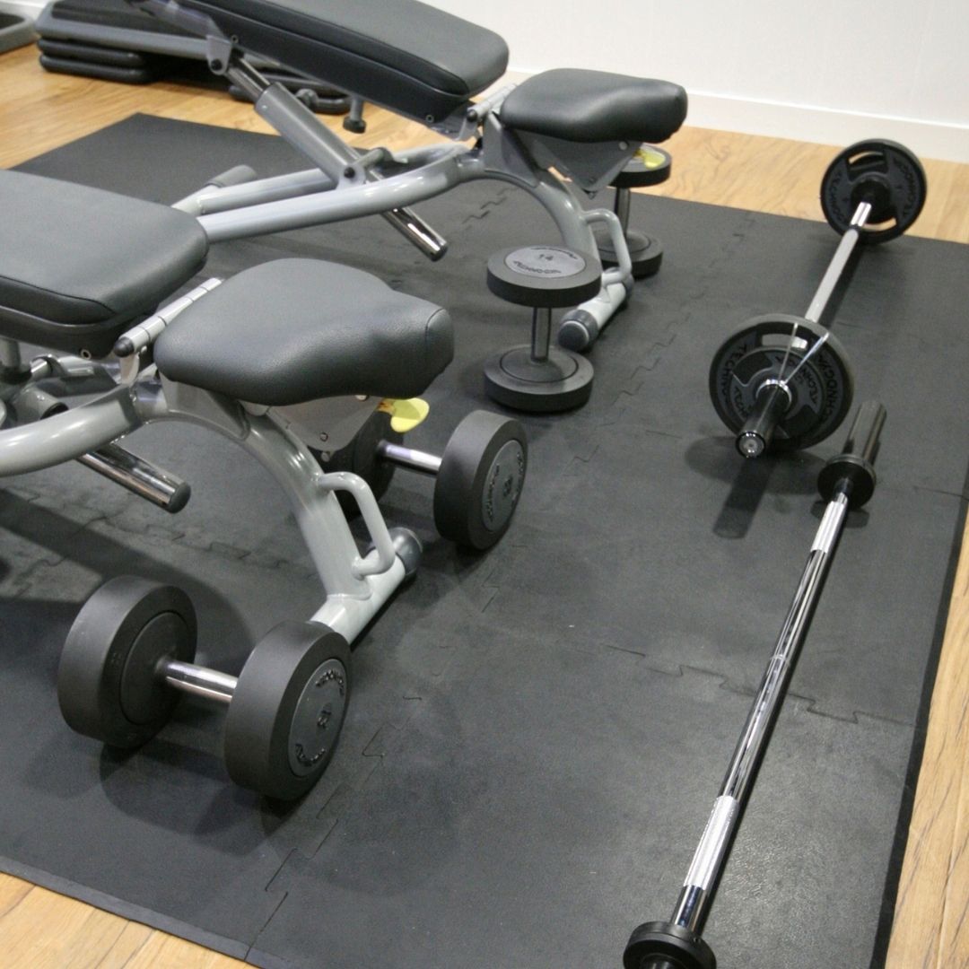Benches and free weights on interlocking gym tiles.