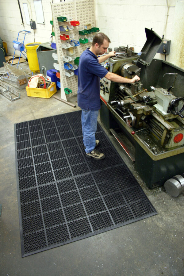 Man working machines whilst on a black mat