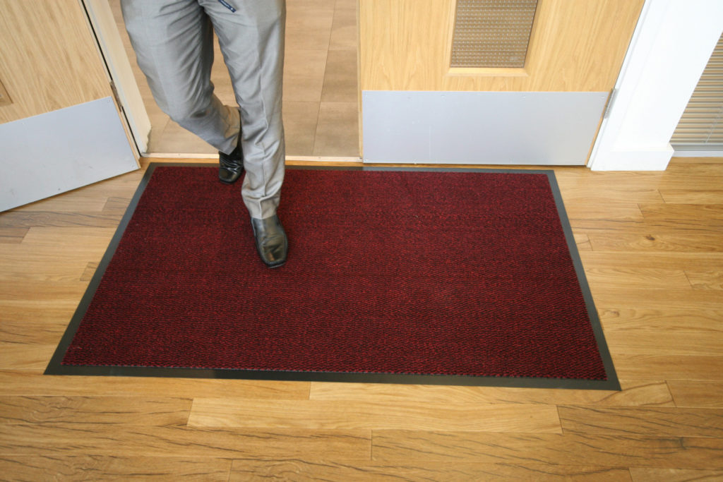 Man walking inside on a red plush doormat