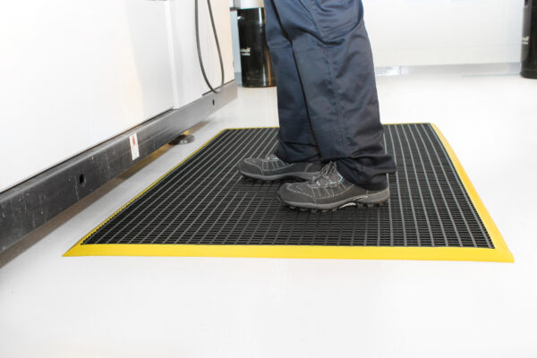 Man standing on black and yellow Workstation mat